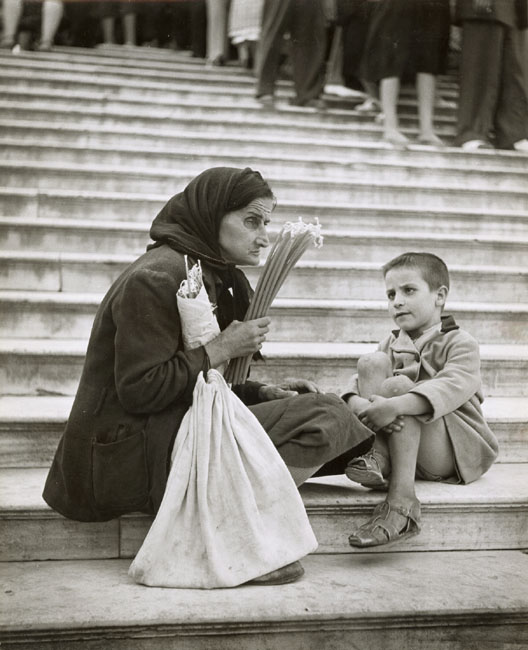 Ernst Haas - Old Woman with Candles and Child on Stairs